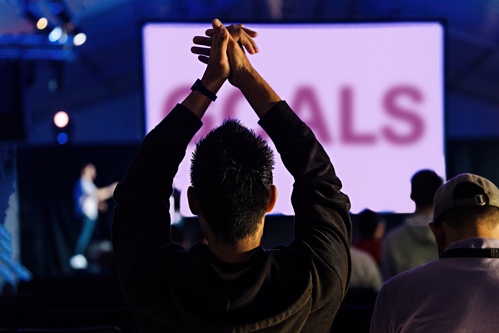 People at a conference or congress viewed from behind, man in foreground applauds warmly with raised